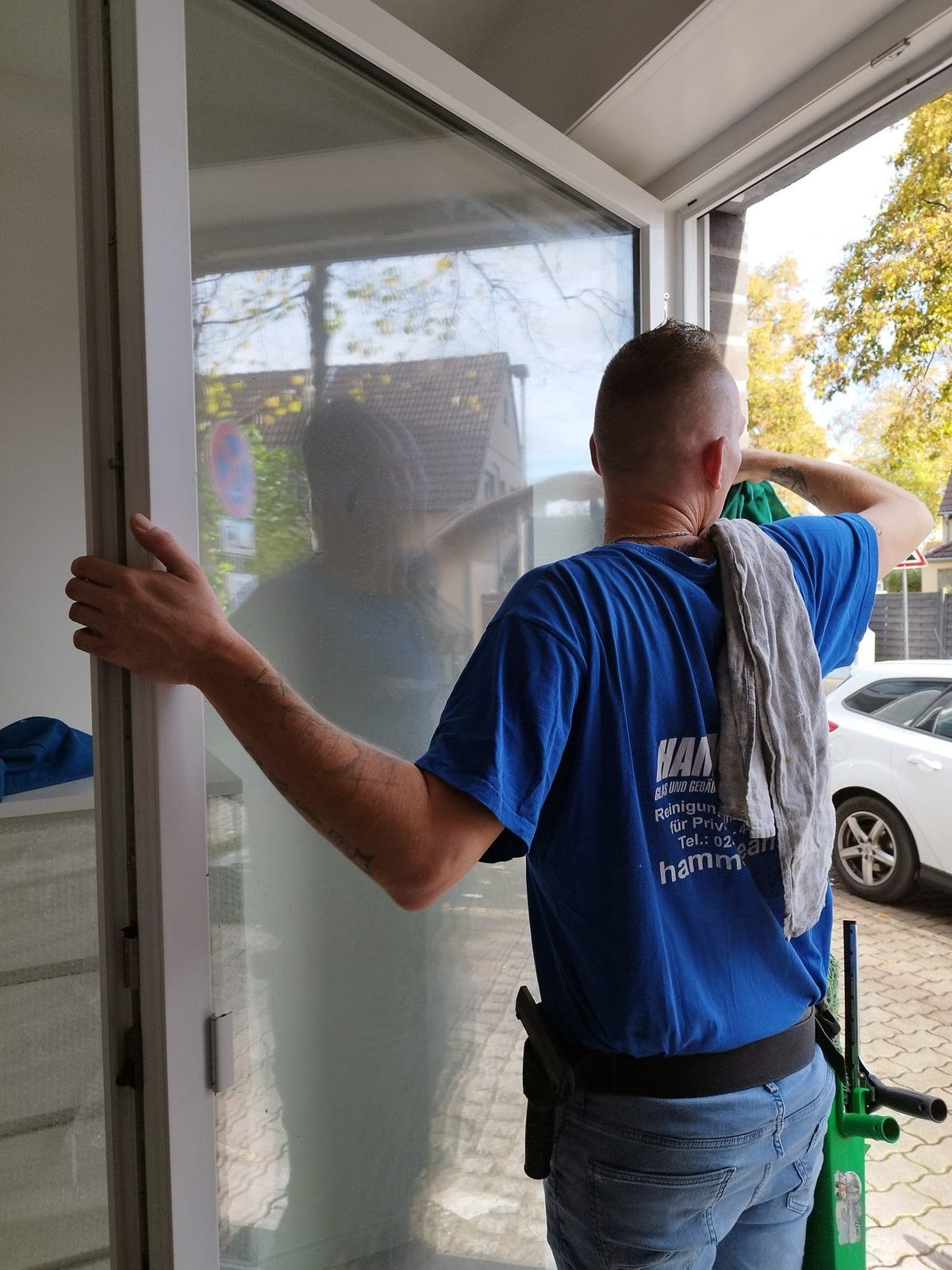 Mitarbeiter im HammClean-T-Shirt reinigt eine Glastür